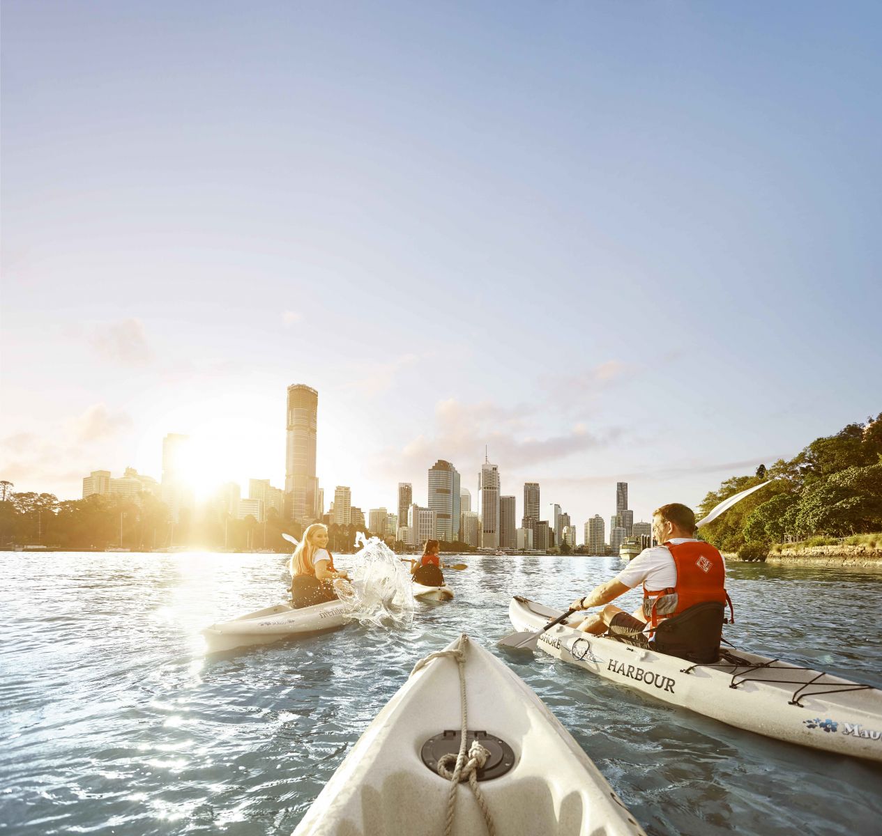 Kayakers on the Brisbane River with the city skyline in the background at sunset
